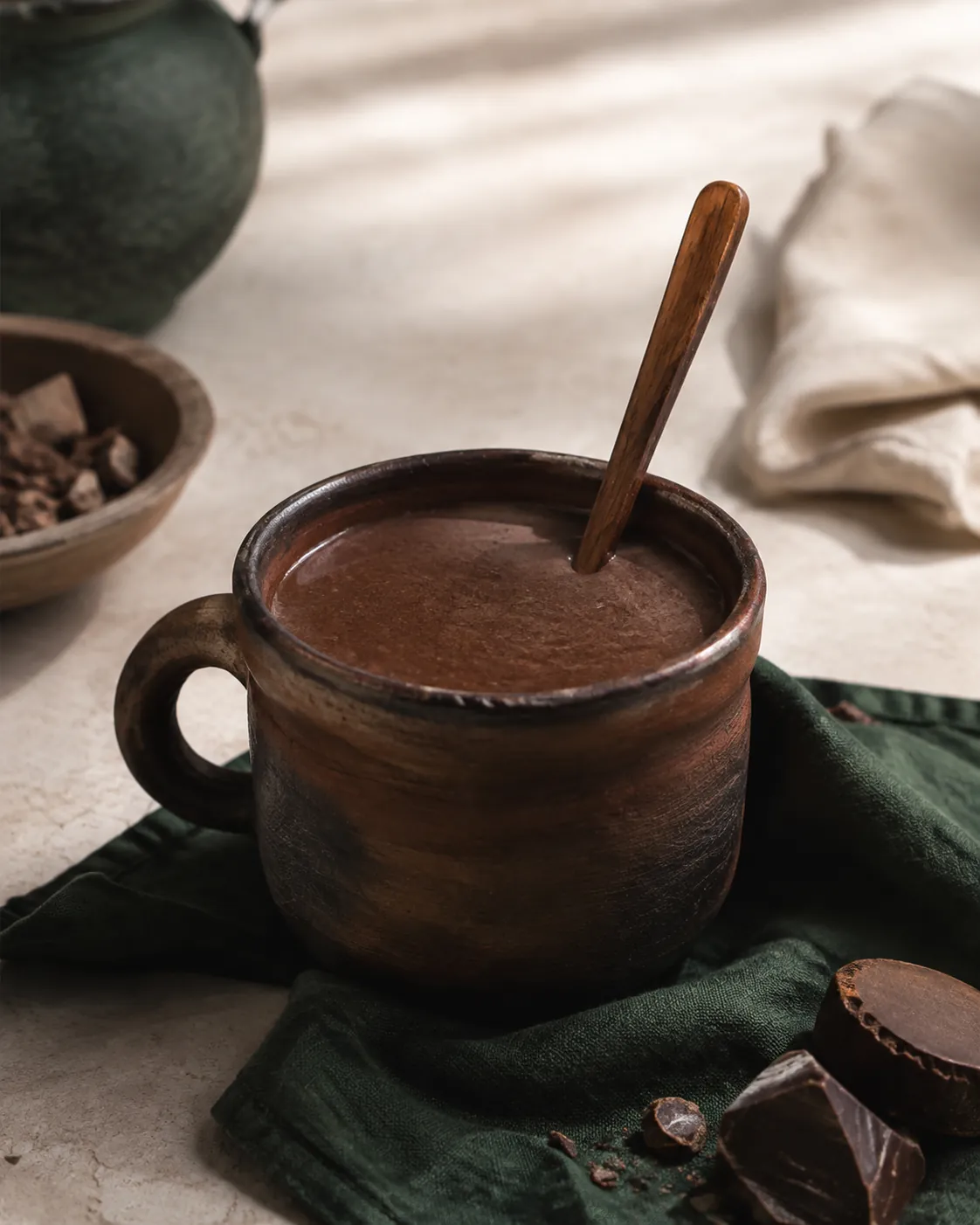 A thick dark champurrado in a clay mug, a spoon standing almost upright in it