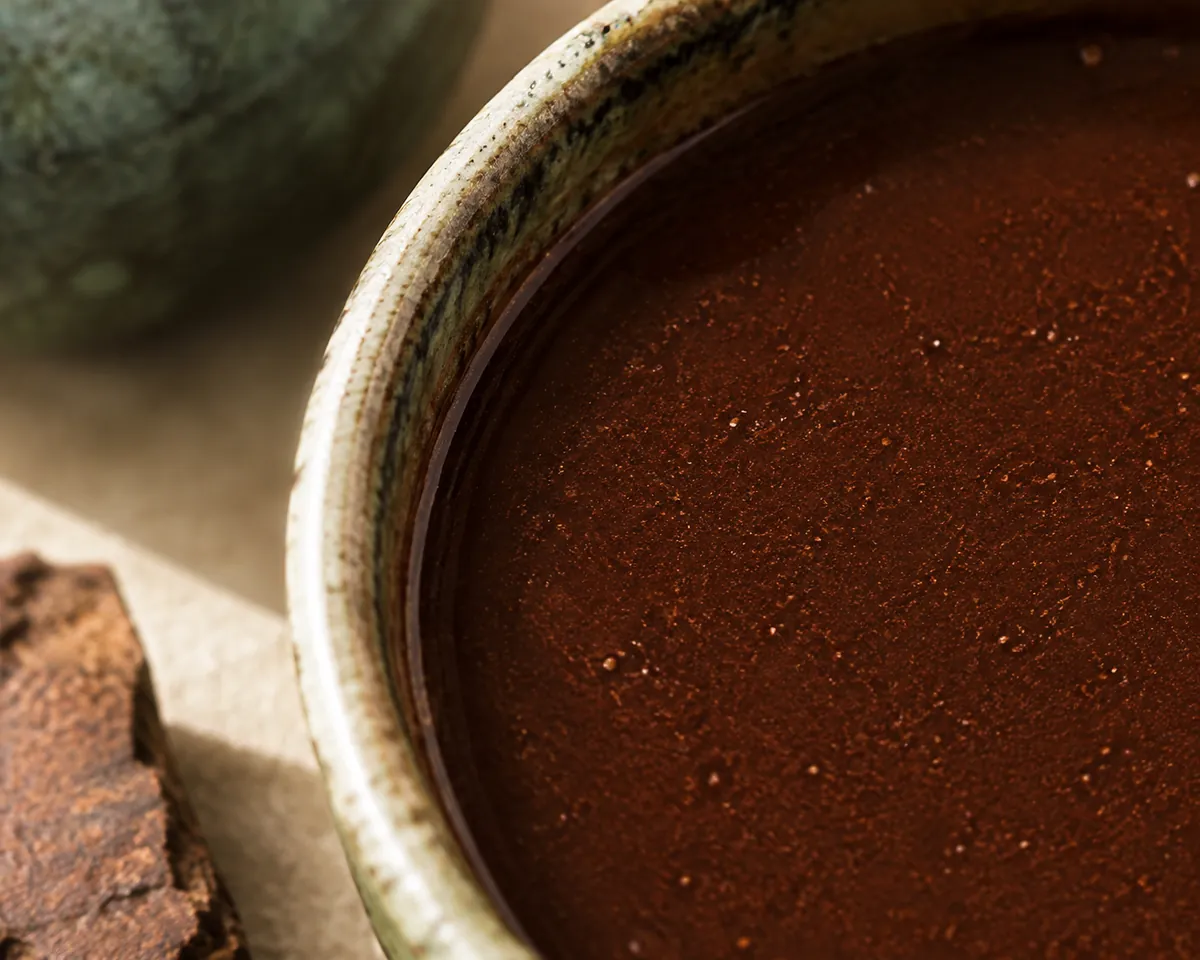 Extreme close view of the surface of a cup of Mexican chocolate showing fine undissolved grit suspended in it