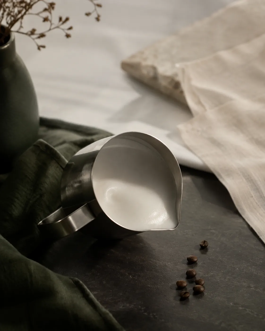 A steel jug tilted to show a glossy microfoam surface with no large bubbles
