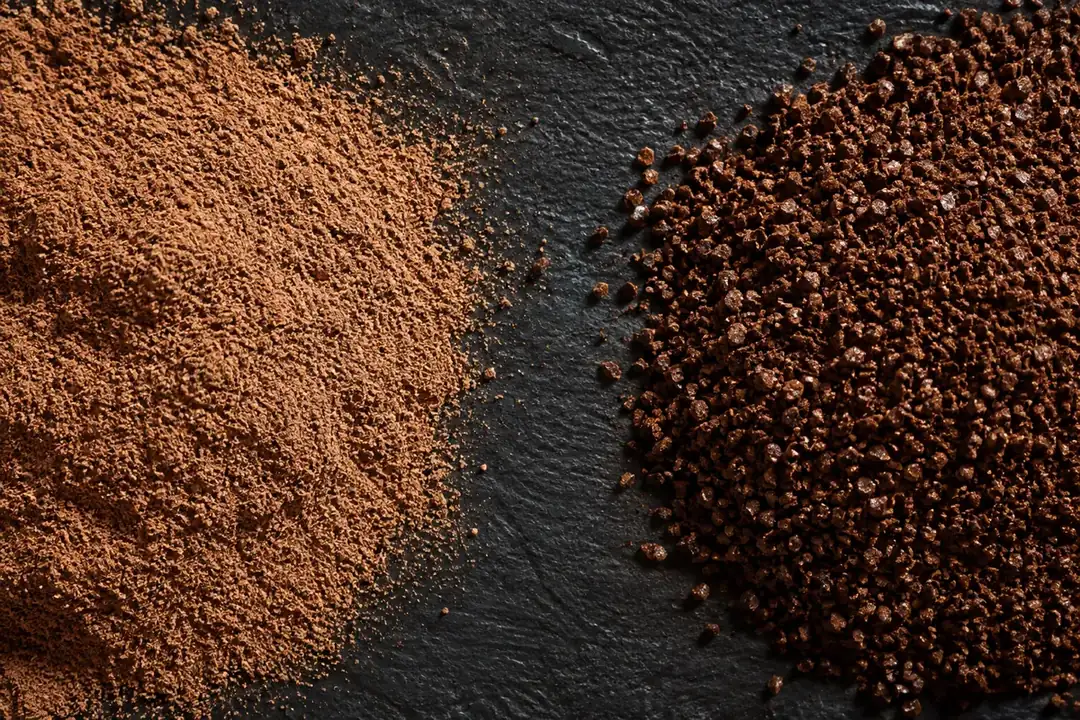 Two heaps of ground coffee on dark slate, the left an extremely fine pale powder like icing sugar and the right a coarser darker grind