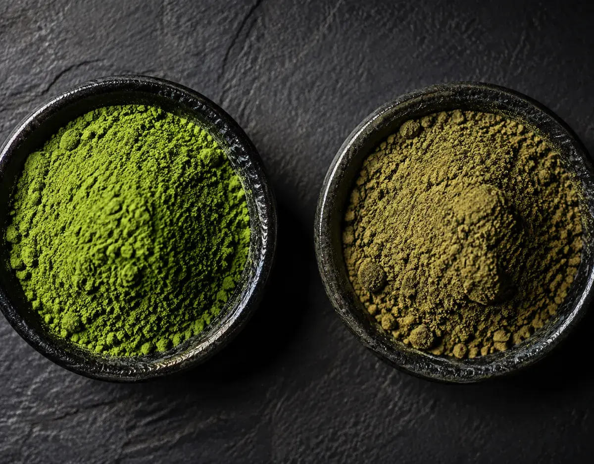 A sealed opaque matcha tin with its lid beside it and a small dish of vivid green powder on a pale surface