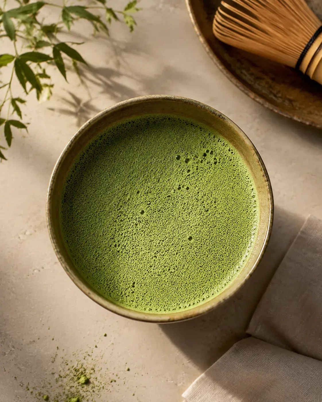 Close view of a bowl of thin matcha with a fine even layer of pale green foam covering the surface