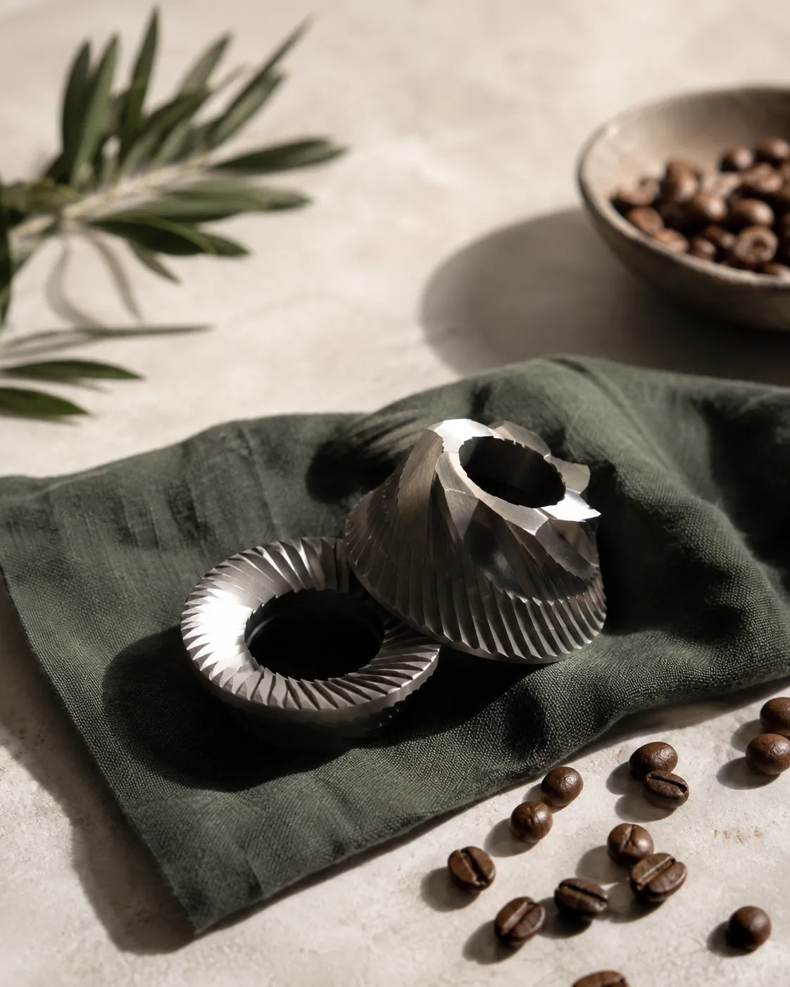 A pair of conical burrs removed from a grinder resting on a cloth