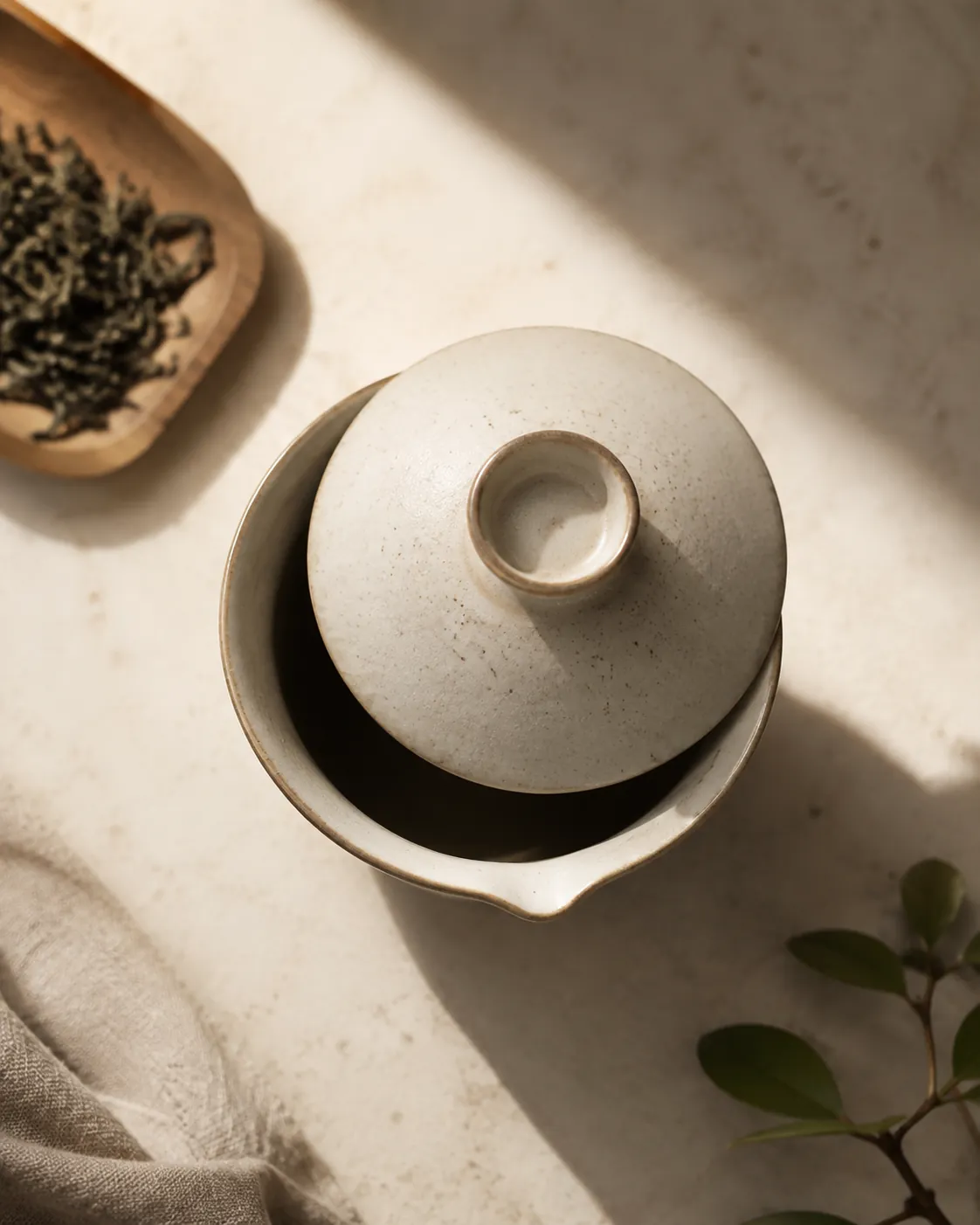 A porcelain gaiwan lid resting slightly askew on the bowl, showing the pouring gap