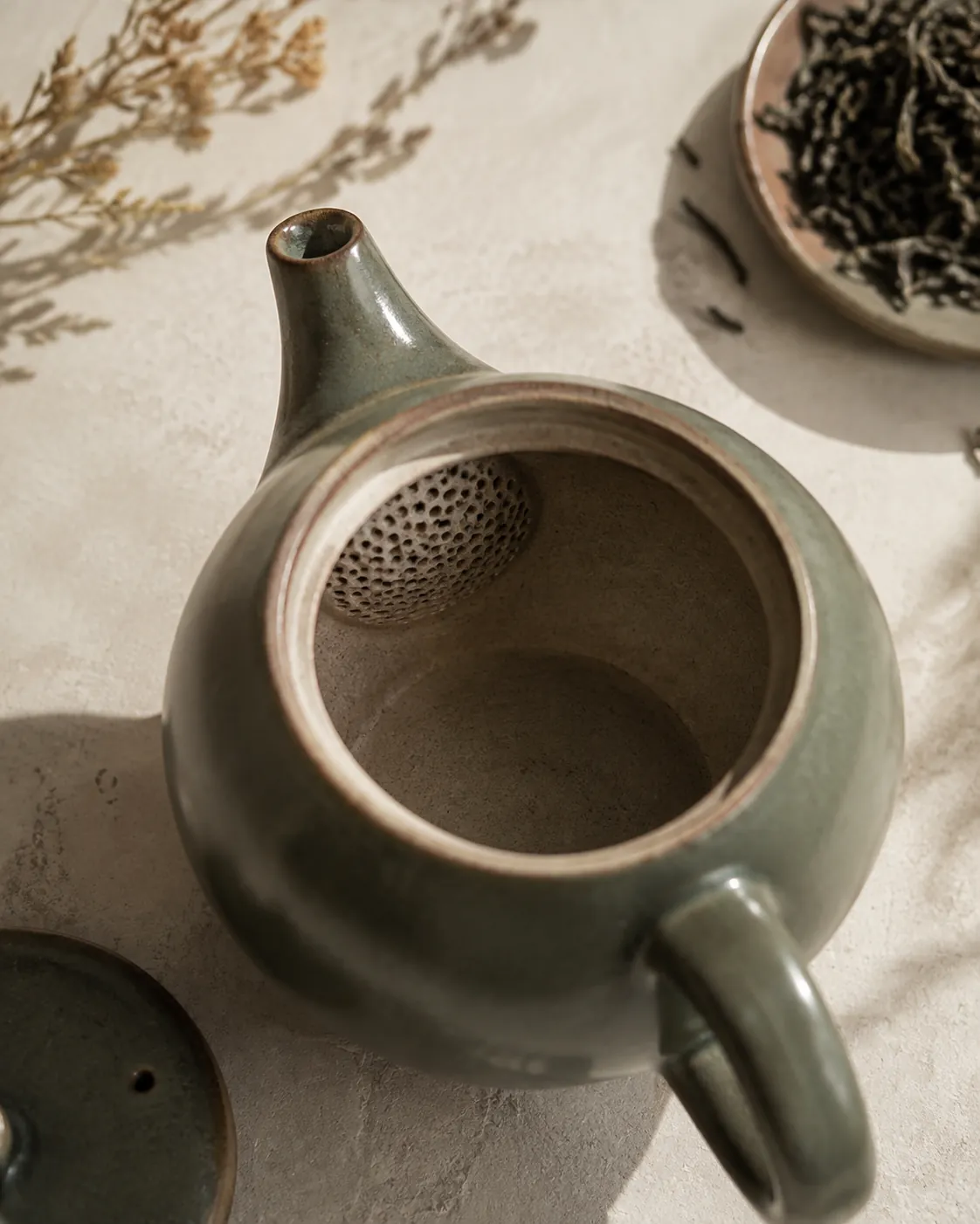 Looking down into an empty teapot at the fine perforated ceramic screen set into the wall where the spout begins