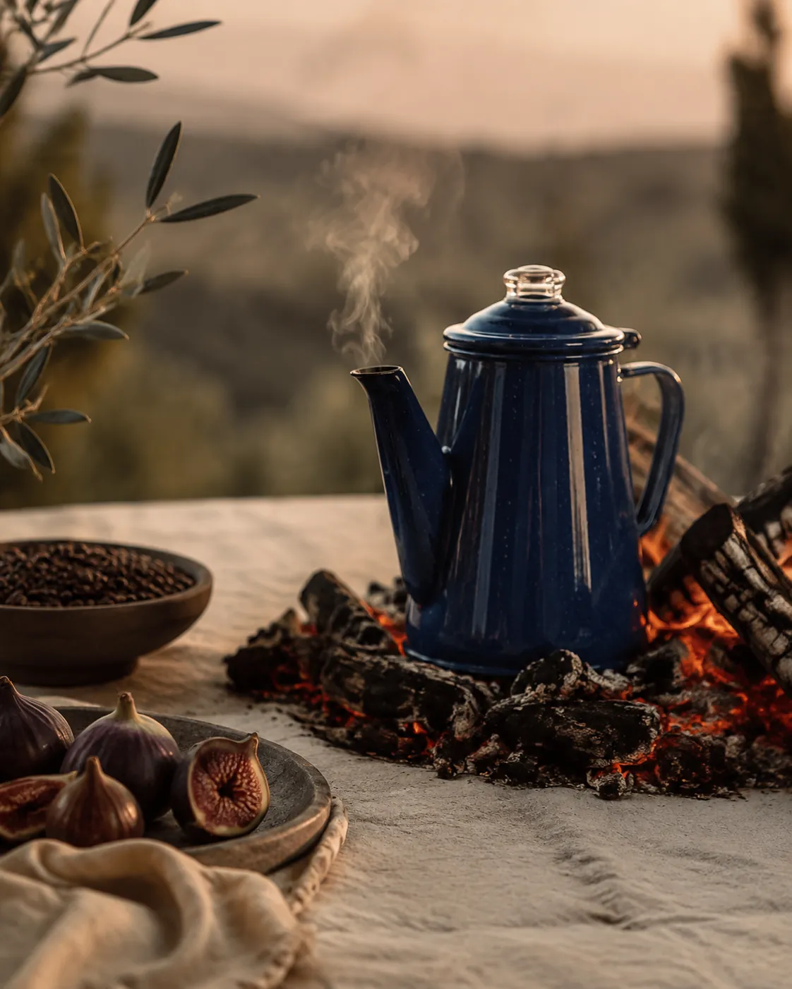 A blue enamel camping percolator sitting among glowing embers at the edge of a fire, steam rising from the spout