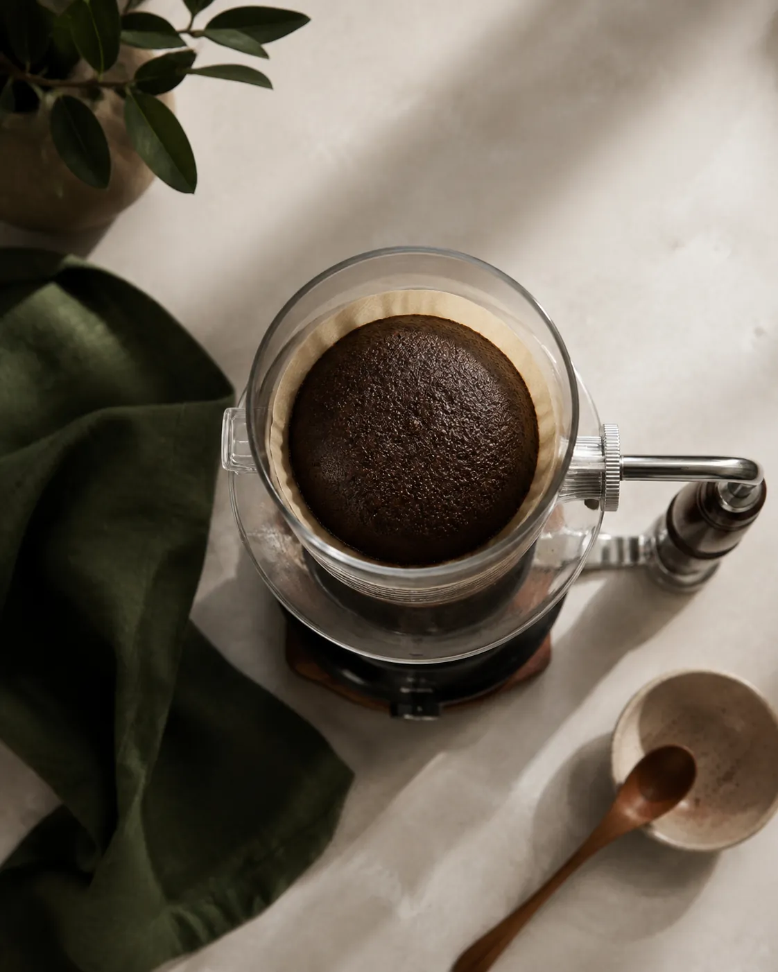 A smooth even dome of spent coffee grounds resting on the filter inside the upper chamber of a siphon brewer