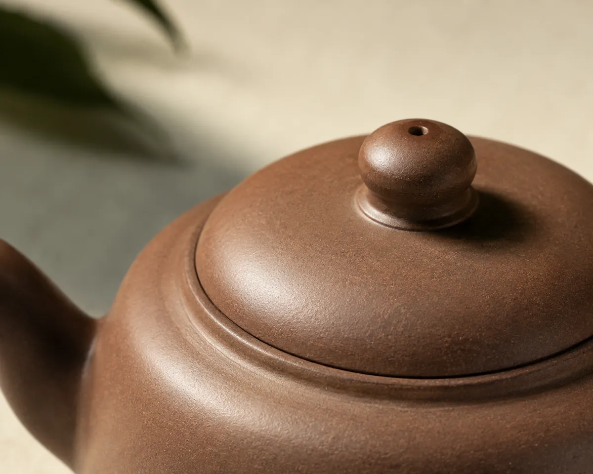 A close view of a clay teapot lid seated in its rim, the gap between lid and pot even all the way round