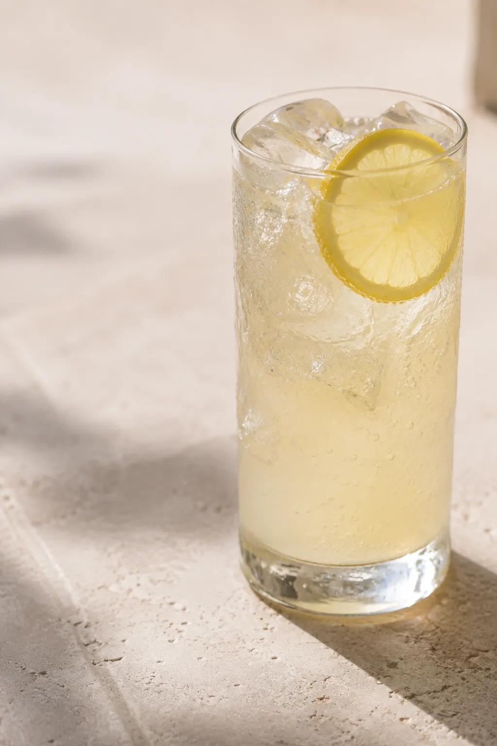 A tall glass of cloudy pale bitter lemon with a slice of lemon