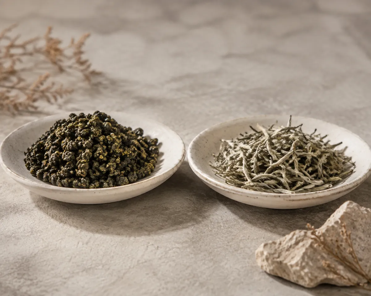 Two shallow dishes side by side, one holding tightly rolled dark oolong pellets and the other holding open downy silver-white tea leaf