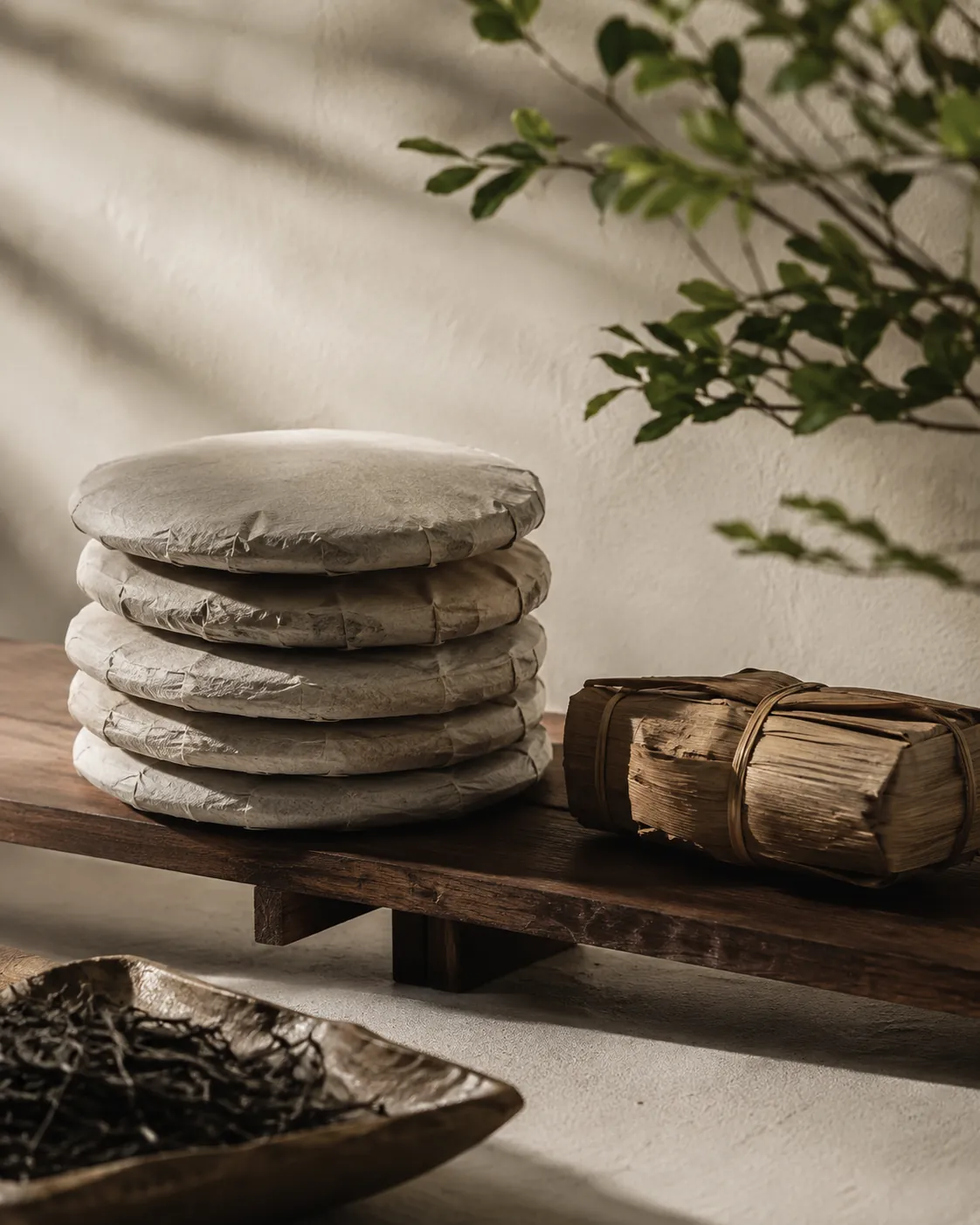 Several wrapped pu-erh cakes stacked on a shelf in their paper wrappers