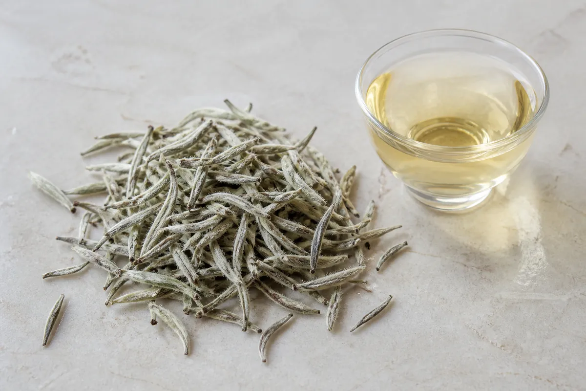 Downy silver white tea buds on a pale stone surface
